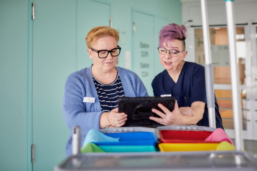 Reinigungskraft mit Tablet auf einer Station