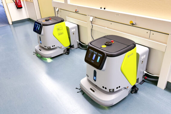 Zwei Reinigungsroboter an ihren Dockingstationen auf einem Klinikflur